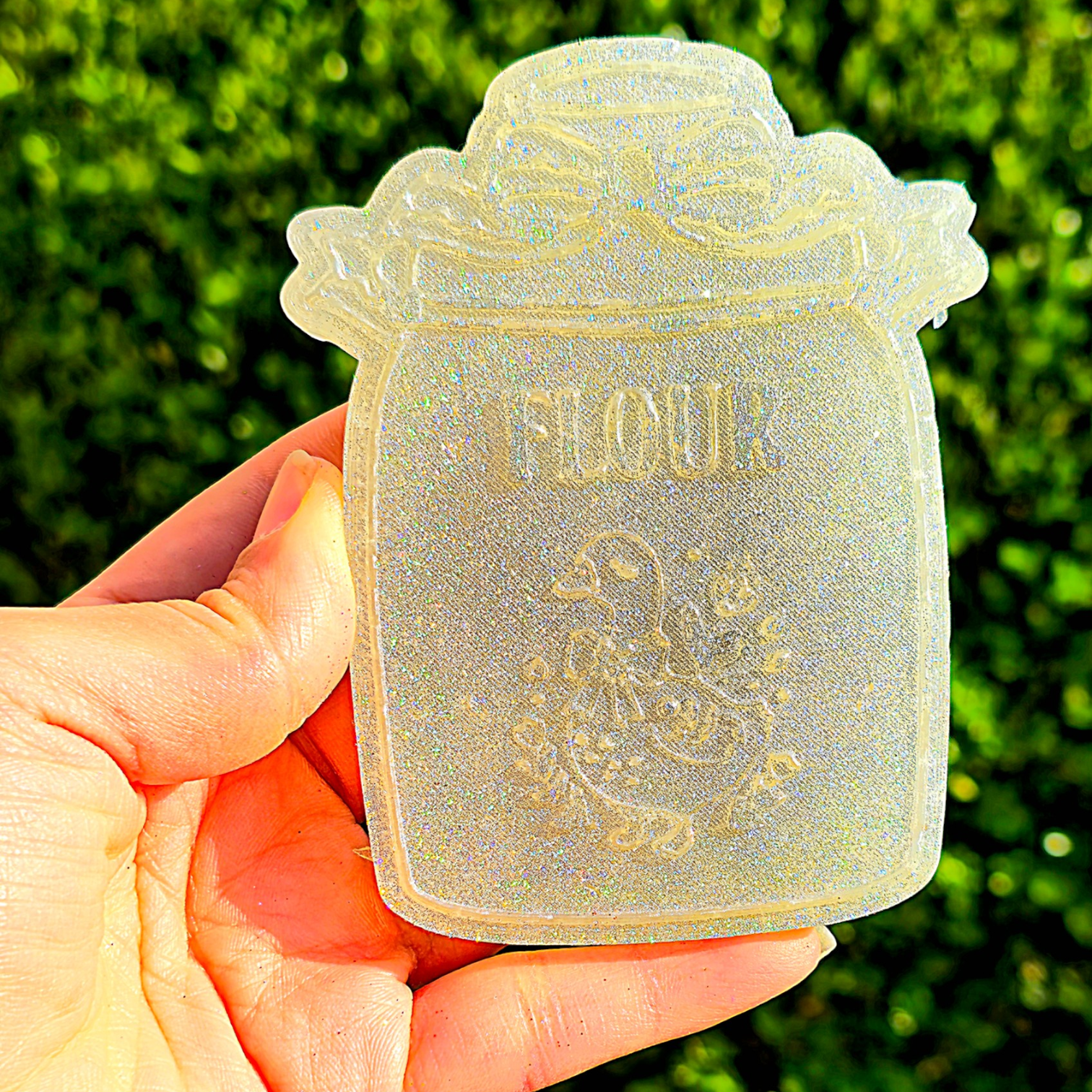 Hand holding a decorative flour container with a green blurred background