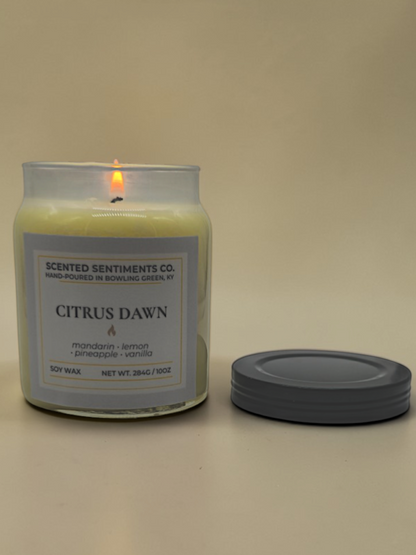 Candle labeled 'Citrus Dawn' from 'Scented Sentiments Co.' on a beige background
