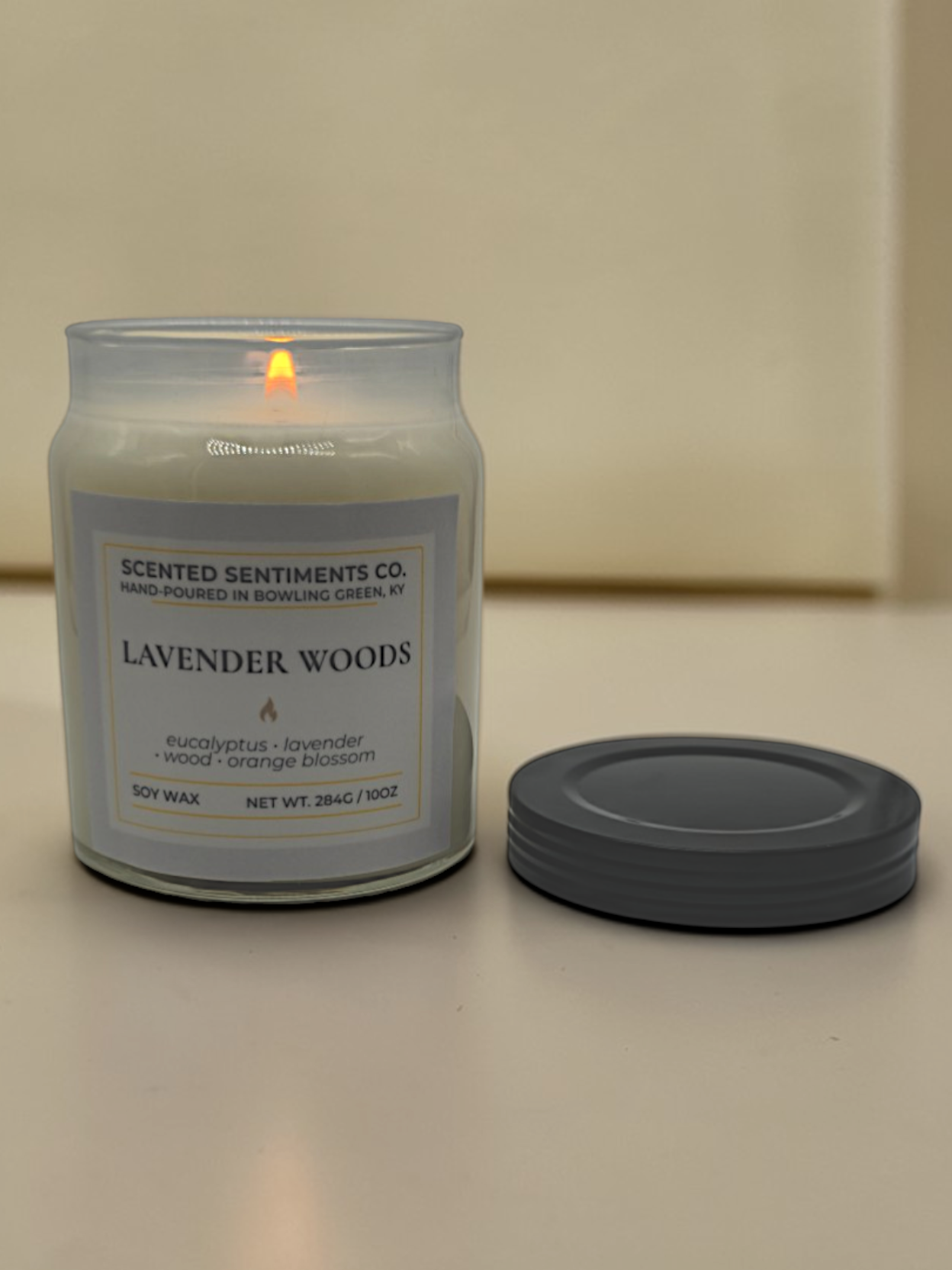 Candle labeled 'Lavender Woods' from 'Scented Sentiments Co.' on a neutral background